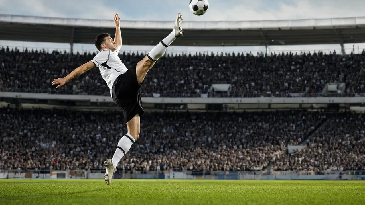 Fußballspieler im Sprung zum Fallrückzieher mit rundem Ball am Fuß vor vollem Stadion