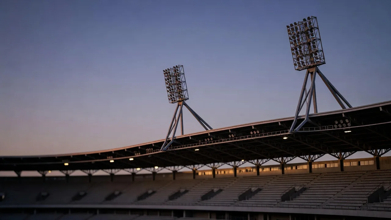 Flutlichtmasten über einem leeren Stadiondach bei einsetzender Dämmerung