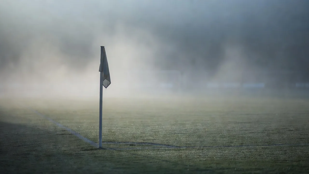 Eckfahne im Morgennebel mit unscharfem Strafraum im Hintergrund