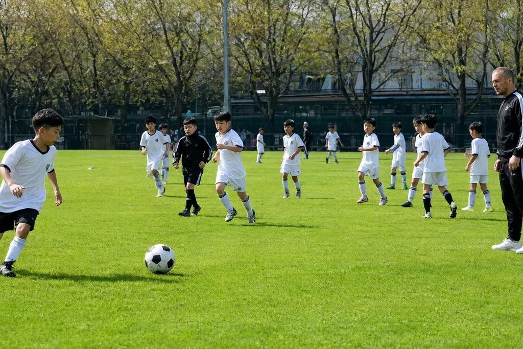 Jugendspieler am Ball im Nachwuchsspiel auf dem Rasen, Trainer an der Linie