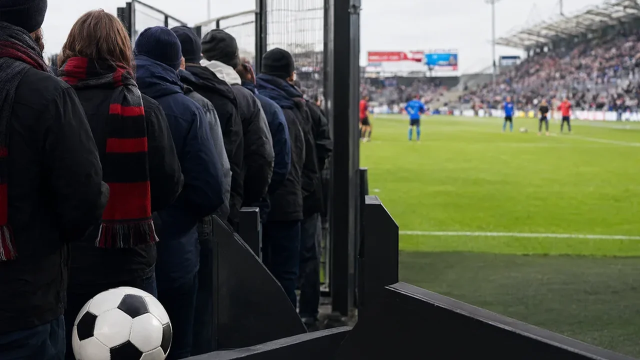 Fußballfans mit Schals in der Schlange an einem Stadioneingang vor dem Anpfiff